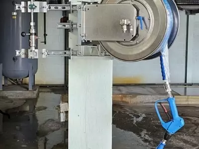 High-pressure stainless steel hose reel and trigger gun mounted to a support column as part of the washdown system at an industrial site in Burton.
